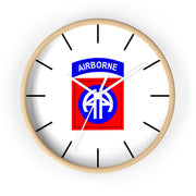 The 82nd Airborne Wall Clock boasts a light wooden frame and a silent clock mechanism. At its center, it prominently displays the 82nd Airborne Division insignia: "AIRBORNE" in blue on a white arch above a blue "AA" on a red background. Black tick marks are used for the hours, making it an excellent addition to any personalized environment.