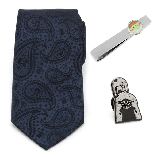 Displayed as the Mando The Child Necktie Gift Set, this package includes a 100% silk navy blue paisley-patterned necktie, a silver tie clip adorned with a small cartoon of a baby in a green blanket, and an enamel lapel pin illustrating the Mandalorian in silver armor holding a tiny character robed in green.