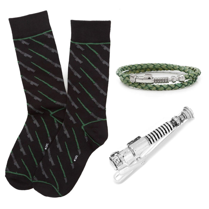 The Luke Skywalker Lightsaber Gift Set, authorized by Lucasfilm LTD, includes a pair of black socks with a green lightsaber design, an olive green braided bracelet with a metallic clasp, and a keychain shaped like Luke Skywalker's lightsaber. This collection is neatly arranged on a plain white background.