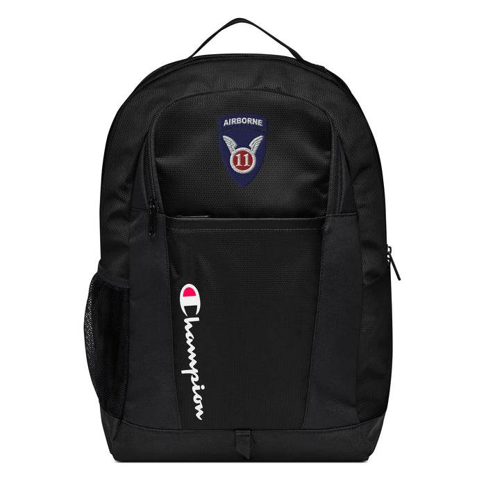 The 11th Airborne Division Champion Backpack in black showcases a "Champion" logo, a mesh side pocket, a top handle and a 11th Airborne Division logo on the front. Crafted from water-resistant material, this sports backpack is ideal for all-weather use.