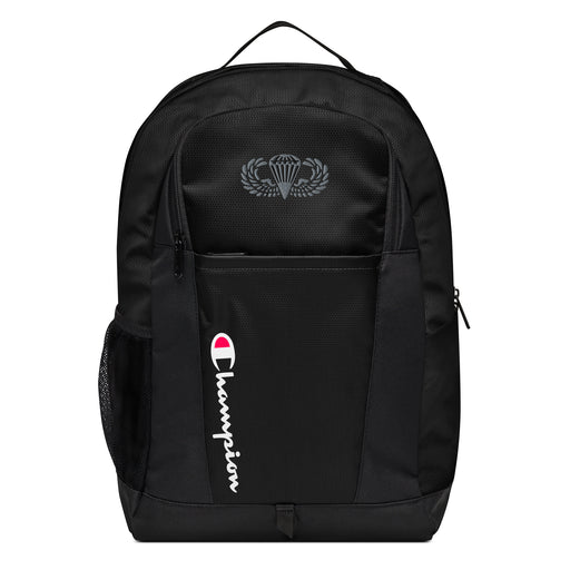 The Basic Parachutist Champion Backpack in black showcases a "Champion" logo, a mesh side pocket, a top handle and a Basic Parachutist logo on the front. Crafted from water-resistant material, this sports backpack is ideal for all-weather use.