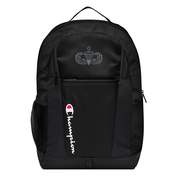 The Senior Parachutist Champion Backpack in black showcases a "Champion" logo, a mesh side pocket, a top handle and a Senior Parachutist logo on the front. Crafted from water-resistant material, this sports backpack is ideal for all-weather use.