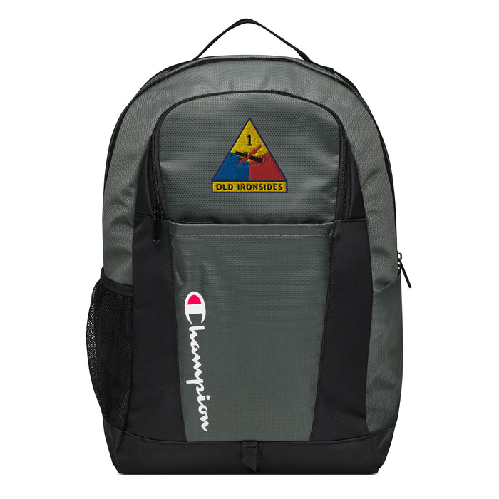 The 1st Armored Division Champion Backpack in gray and black showcases a "Champion" logo, a mesh side pocket, a top handle and a 1st Armored Division logo on the front. Crafted from water-resistant material, this sports backpack is ideal for all-weather use.