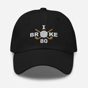 The "I Broke 80" Men's Embroidered Hat is a black, low-profile hat featuring the phrase "I Broke 70" on the front. The word "Broke" is uniquely stylized with a golf ball as the 'O' and crossed golf clubs beneath it.