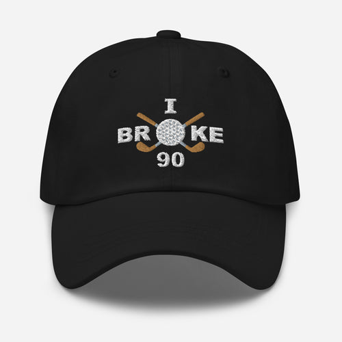 The "I Broke 90" Men's Embroidered Hat is a black, low-profile hat featuring the phrase "I Broke 70" on the front. The word "Broke" is uniquely stylized with a golf ball as the 'O' and crossed golf clubs beneath it.