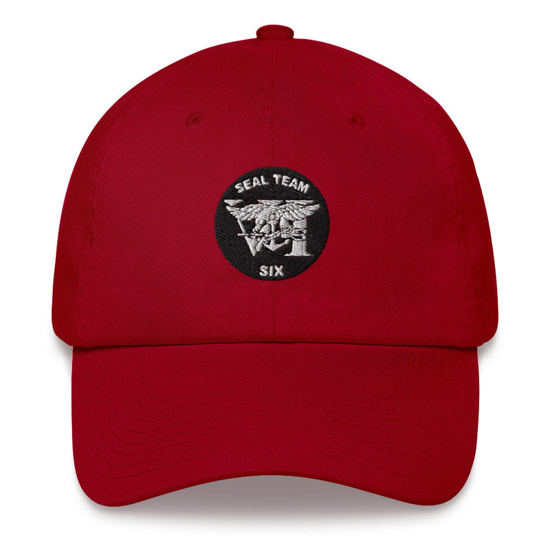 A cranberry colored Seal Team 6 Hat with the logo on the front.  The hat has a curved visor and an adjustable strap at the back.