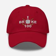 The "I Broke 100" Men's Embroidered Hat is a cranberry, low-profile hat featuring the phrase "I Broke 70" on the front. The word "Broke" is uniquely stylized with a golf ball as the 'O' and crossed golf clubs beneath it.