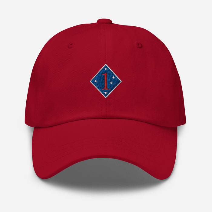 A cranberry colored 1st Marine Division Hat with the logo on the front.  The hat has a curved visor and an adjustable strap at the back.
