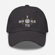The "I Broke 70" Men's Embroidered Hat is a dark grey, low-profile hat featuring the phrase "I Broke 70" on the front. The word "Broke" is uniquely stylized with a golf ball as the 'O' and crossed golf clubs beneath it.