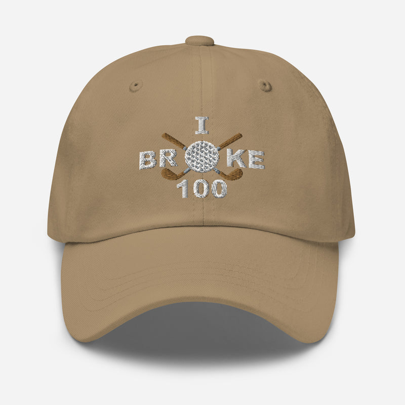 The "I Broke 100" Men's Embroidered Hat is a khaki colored, low-profile hat featuring the phrase "I Broke 70" on the front. The word "Broke" is uniquely stylized with a golf ball as the 'O' and crossed golf clubs beneath it.