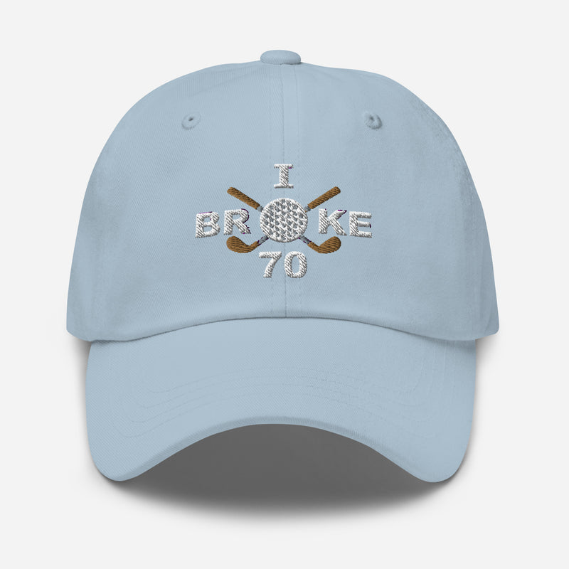 The "I Broke 70" Men's Embroidered Hat is a light blue, low-profile hat featuring the phrase "I Broke 70" on the front. The word "Broke" is uniquely stylized with a golf ball as the 'O' and crossed golf clubs beneath it.