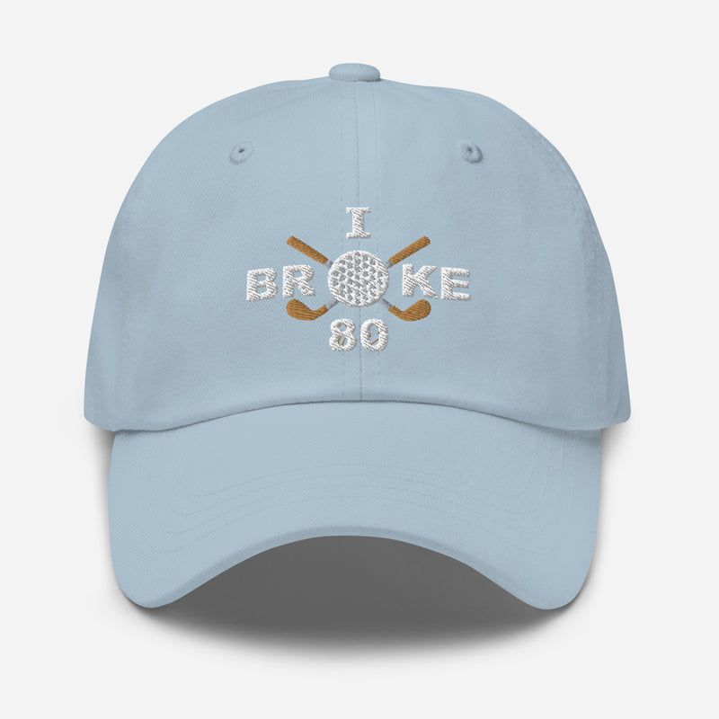 The "I Broke 80" Men's Embroidered Hat is a light blue, low-profile hat featuring the phrase "I Broke 70" on the front. The word "Broke" is uniquely stylized with a golf ball as the 'O' and crossed golf clubs beneath it.