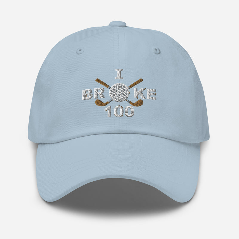 The "I Broke 100" Men's Embroidered Hat is a light blue, low-profile hat featuring the phrase "I Broke 70" on the front. The word "Broke" is uniquely stylized with a golf ball as the 'O' and crossed golf clubs beneath it.