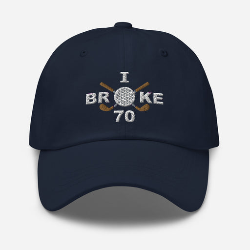 The "I Broke 70" Men's Embroidered Hat is a navy, low-profile hat featuring the phrase "I Broke 70" on the front. The word "Broke" is uniquely stylized with a golf ball as the 'O' and crossed golf clubs beneath it.