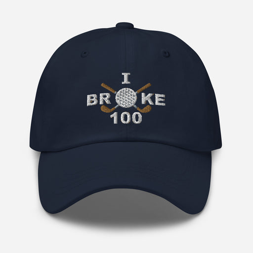 The "I Broke 100" Men's Embroidered Hat is a navy, low-profile hat featuring the phrase "I Broke 70" on the front. The word "Broke" is uniquely stylized with a golf ball as the 'O' and crossed golf clubs beneath it.