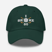 The "I Broke 80" Men's Embroidered Hat is a spruce colored, low-profile hat featuring the phrase "I Broke 70" on the front. The word "Broke" is uniquely stylized with a golf ball as the 'O' and crossed golf clubs beneath it.
