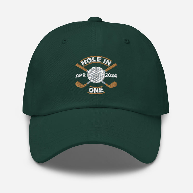 The Golf Hat in spruce colored - Hole in One with Personalized Month and Year features a golf design  including two crossed golf clubs with a golf ball at the center and the text "HOLE IN ONE" above. Customized month and year are on the left and right sides.
