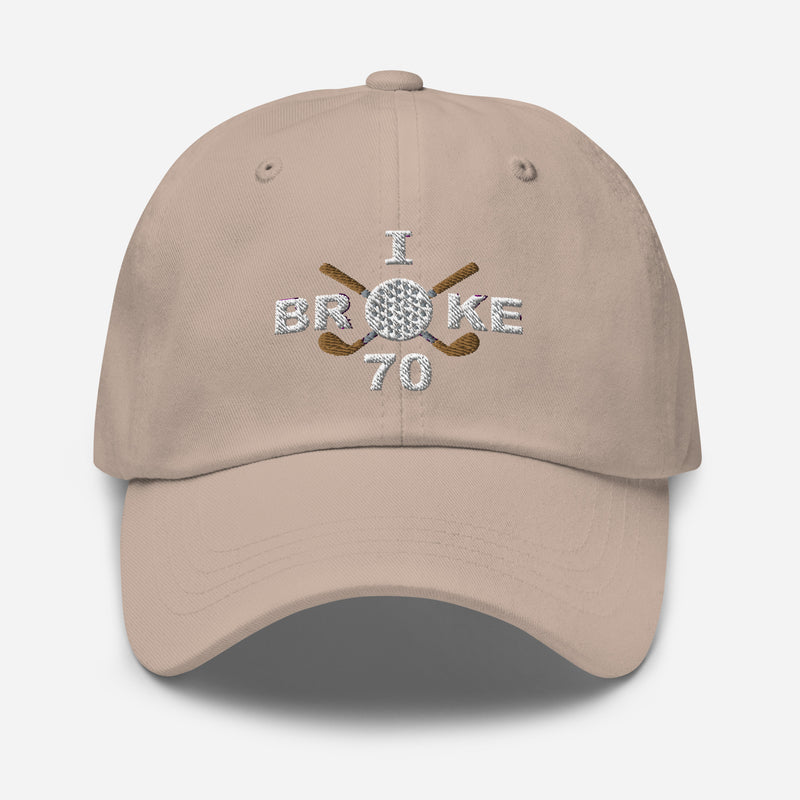 The "I Broke 70" Men's Embroidered Hat is a stone colored, low-profile hat featuring the phrase "I Broke 70" on the front. The word "Broke" is uniquely stylized with a golf ball as the 'O' and crossed golf clubs beneath it.