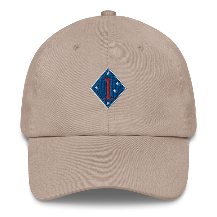 A stone colored 1st Marine Division Hat with the logo on the front.  The hat has a curved visor and an adjustable strap at the back.
