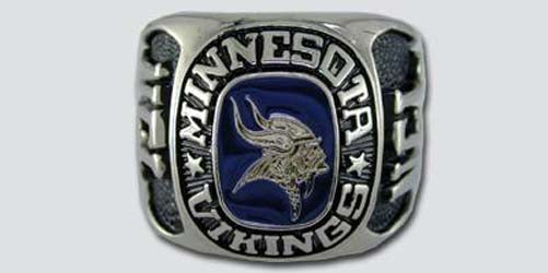 A silver colored paperweight featuring the Minnesota Vikings logo set against a blue enamel background. The words "Minnesota Vikings" are engraved on the bezel.