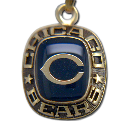 The Chicago Bears Goldtone Pendant with Enamel features a dark blue stone with a silver "C" emblem. Balfour's craftsmanship is highlighted by the engraving of "CHICAGO BEARS" around the stone, accompanied by two stars.