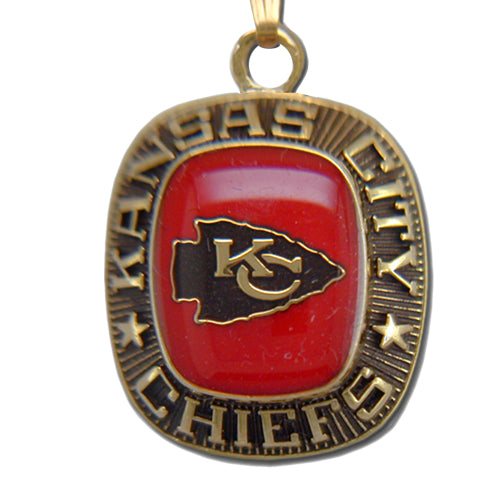 The Kansas City Chiefs Goldtone Pendant with Enamel is a stunning team pendant, featuring a gold and red design that highlights the team's arrowhead logo at its center, with the words "Kansas City Chiefs" engraved around the border.