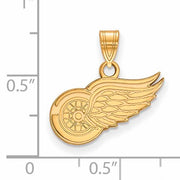 The SS w/GP NHL Detroit Red Wings Small Pendant is a Gold-Plated Sterling Silver pendant designed to resemble a wheel with a feathered wing. It features a loop at the top for easy attachment to a necklace, and based on the ruler scale in the background, the pendant measures approximately 0.5 inches in width and 0.75 inches in height.