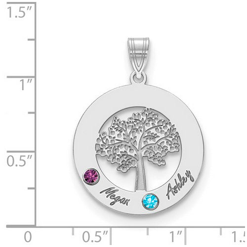 The Circle Pendant With 2 Birthstones is a quality silver accessory featuring a detailed tree in the center. It includes two colored gems: one purple (A) and one blue (B). "Megan" is engraved next to gem A, while "Ashley" is engraved next to gem B. This birthstone pendant has a loop at the top for attaching to a necklace chain. The pendant is shown on a ruled background.