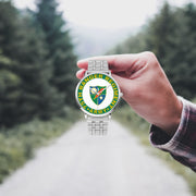 A hand in a plaid shirt holds the 75th Ranger Regiment Silvertone Watch against the background of a blurred forest scene, where a path runs through the center.