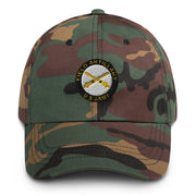 A military style US Army Field Artillery Hat with camouflage and the logo on the front.  The hat has a curved visor and an adjustable strap at the back. 