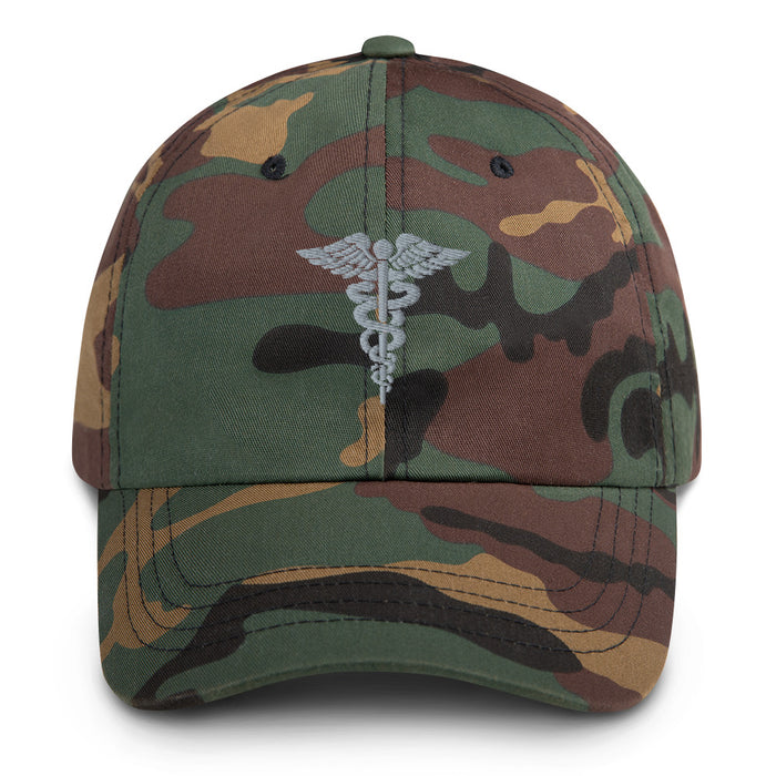 A military style Hospital Corpsman Hat with camouflage and the logo on the front.  The hat has a curved visor and an adjustable strap at the back. 