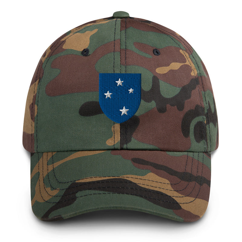 A military style 23rd Infantry Division Hat with camouflage and the logo on the front.  The hat has a curved visor and an adjustable strap at the back. 