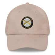 A stone colored US Army Field Artillery Hat with the logo on the front.  The hat has a curved visor and an adjustable strap at the back.