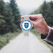 A hand in a plaid shirt holds the 8th Infantry Division Silvertone Watch against the background of a blurred forest scene, where a path runs through the center.