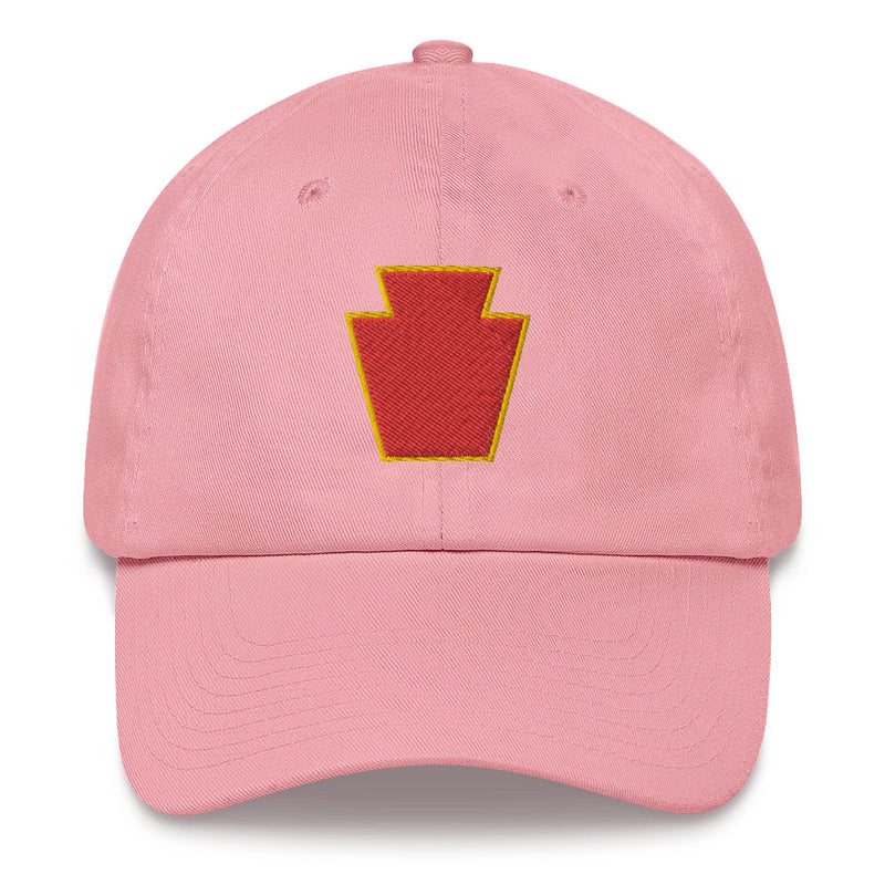 A pink 28th Infantry Division Hat with the logo on the front.  The hat has a curved visor and an adjustable strap at the back.