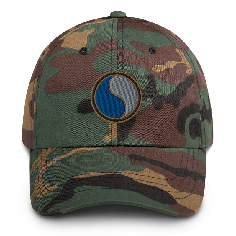 A military style 29th Infantry Division Hat with camouflage and the logo on the front.  The hat has a curved visor and an adjustable strap at the back. 