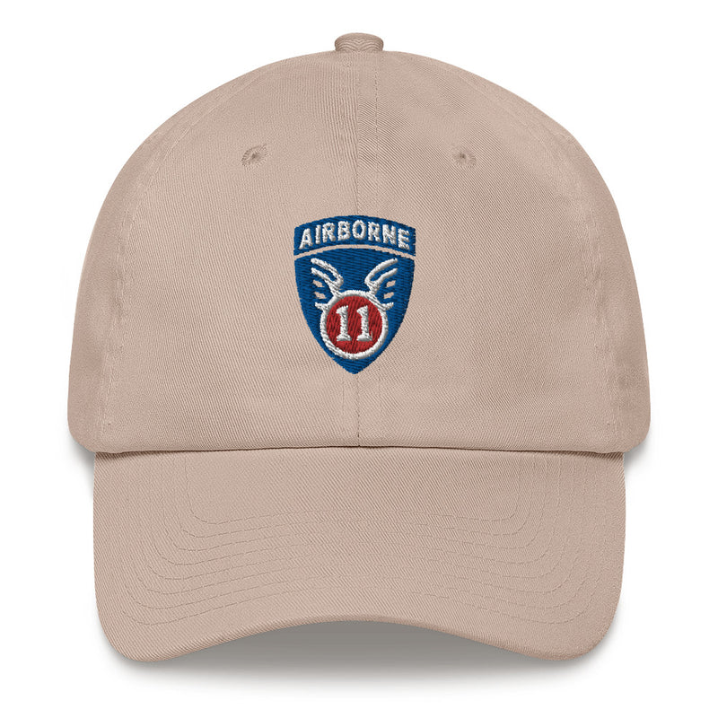 A stone colored 11th Airborne Division Hat with the logo on the front.  The hat has a curved visor and an adjustable strap at the back.