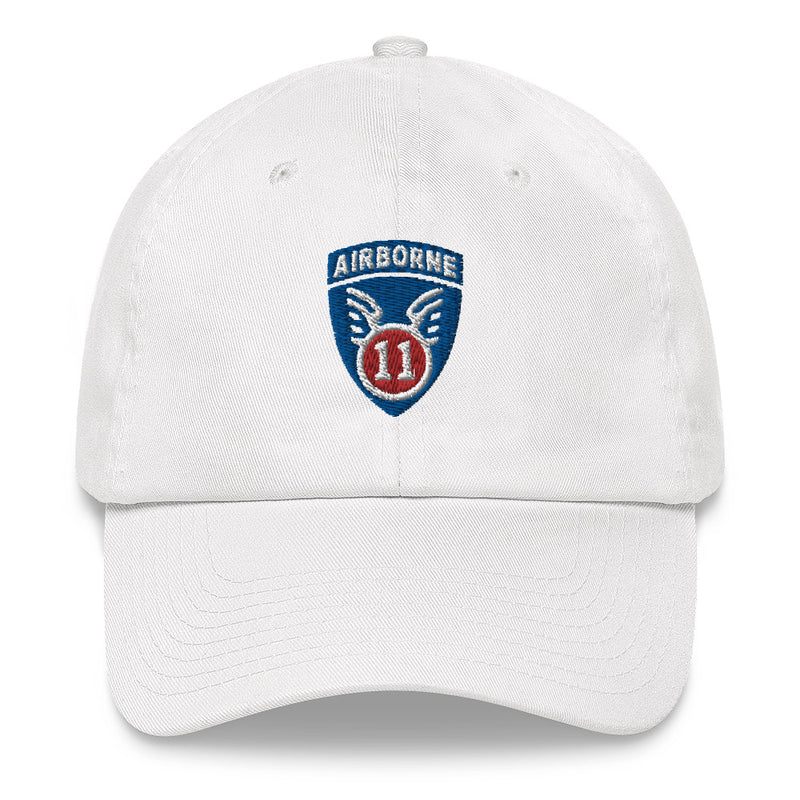 A white 11th Airborne Division Hat with the logo on the front.  The hat has a curved visor and an adjustable strap at the back.